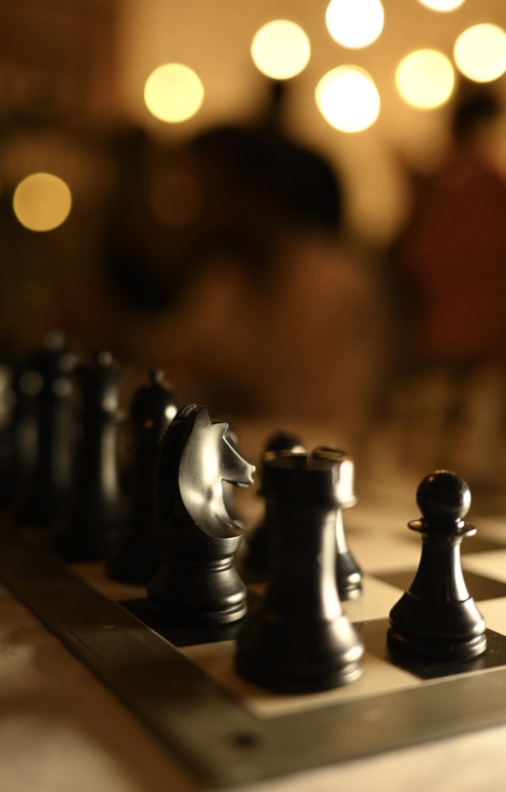 Chess pieces on a board in warm cafe lighting